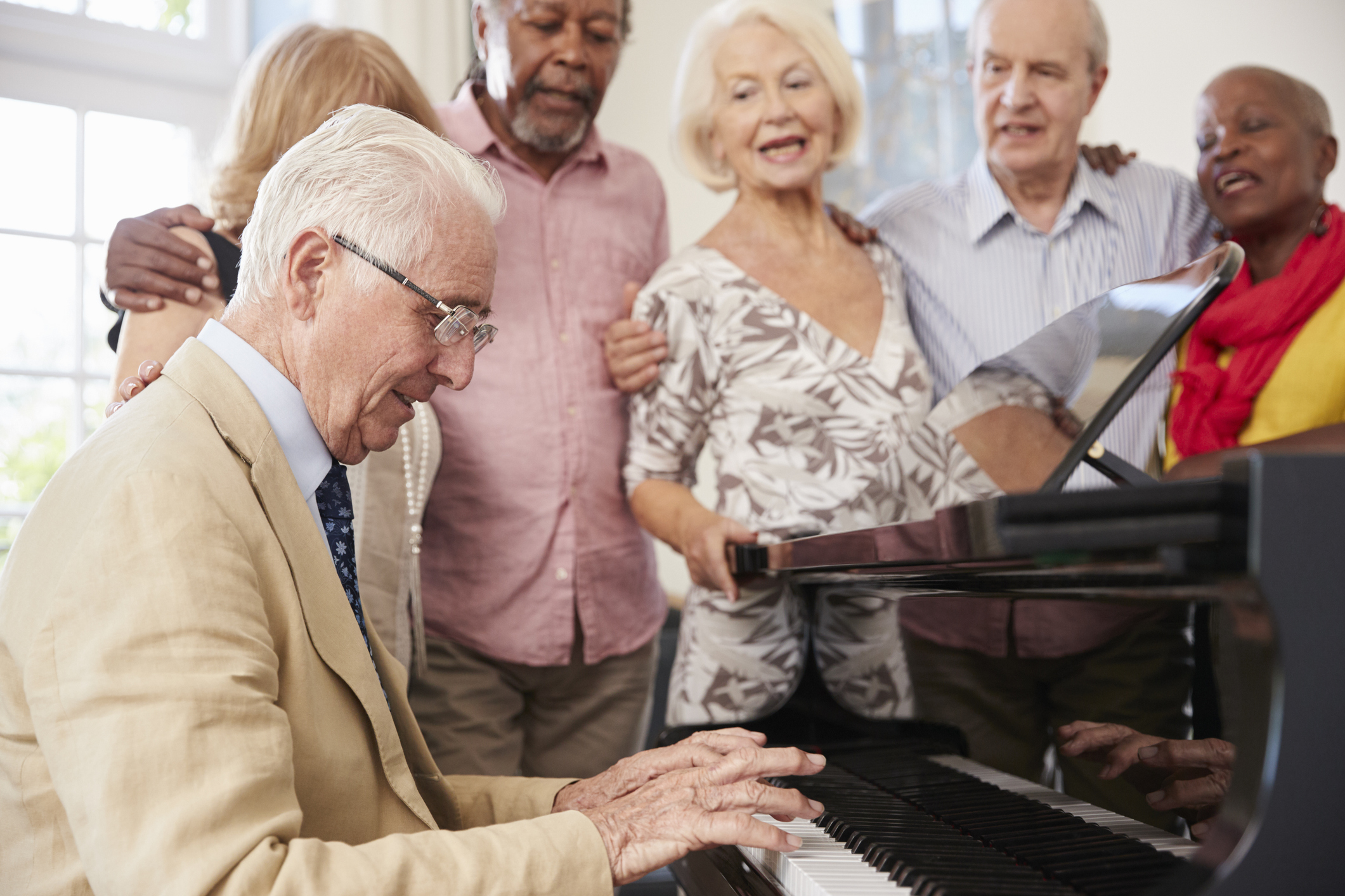 seniors gather around one senior playing a piano