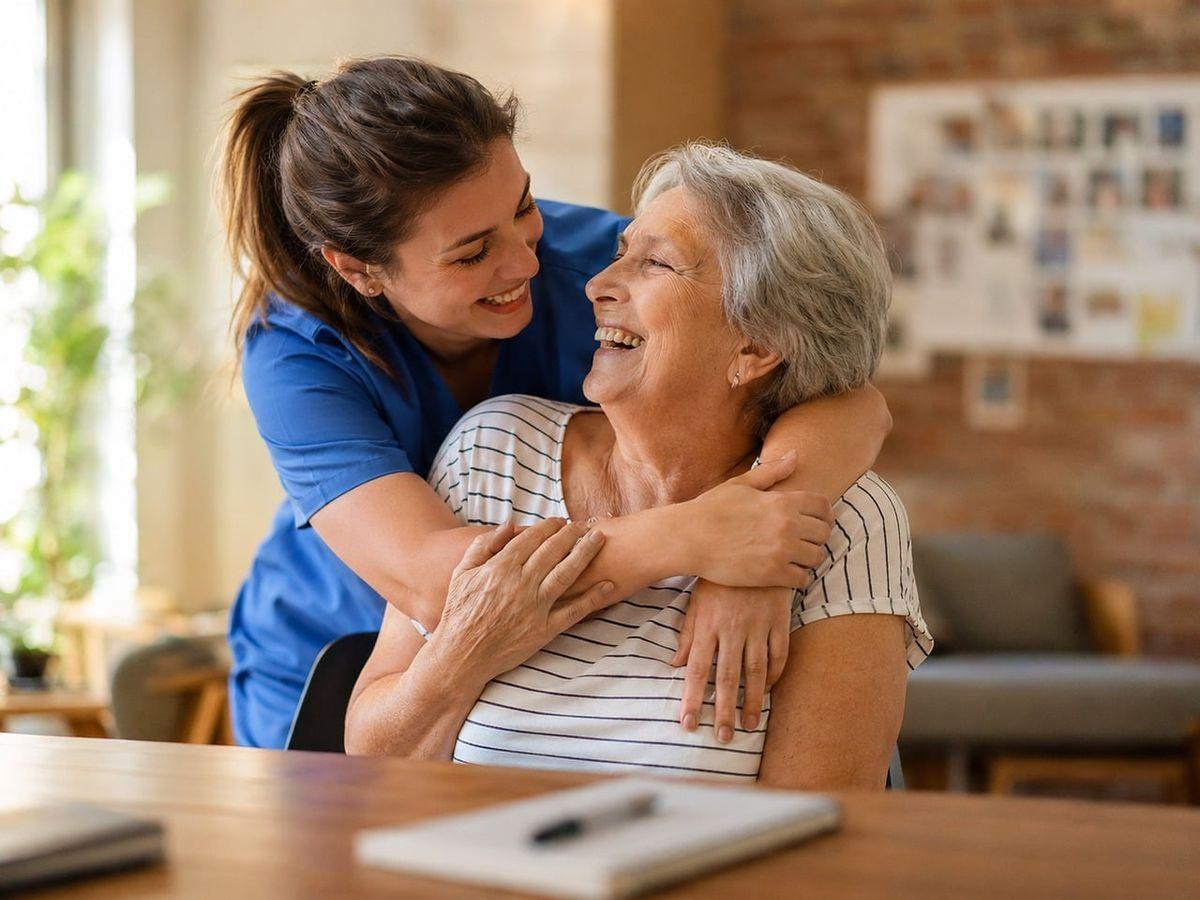 A caregiver giving a senior a hug, both smiling at each other in an assisted living community.